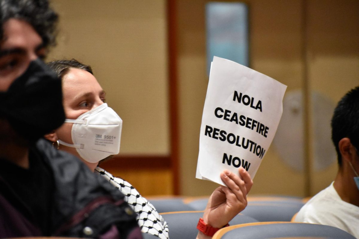 A community member holds a sign reading NOLA CEASEFIRE RESOLUTION NOW in the audience at a New Orleans city council meeting on June 6, 2024.