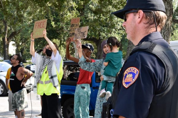 Protesters, including students and community members, hold signs in support of Palestine. A Loyola police officer monitors the situation.