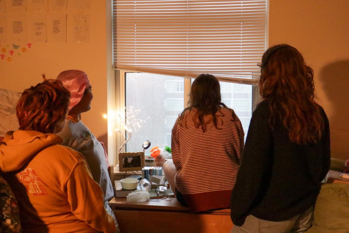 Em Bay, Aria Norman-Gesuelle, August Bay, and Sophie Schnapp look out a Francis Hall window facing the Residential Quad.