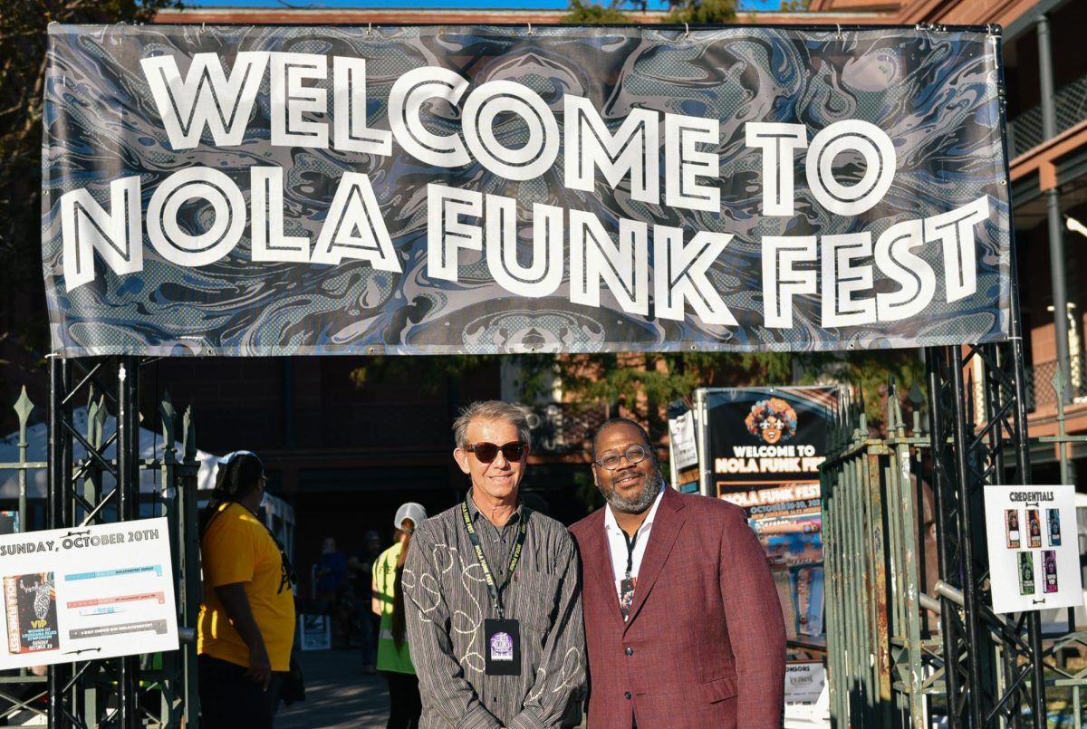 Music industry professor and stage coordinator Jonathan McHugh and Loyola President Xavier Cole pose in front of the Passing the Torch Stage sponsored by the College of Music and Media. Cole performed music with students at the festival. 