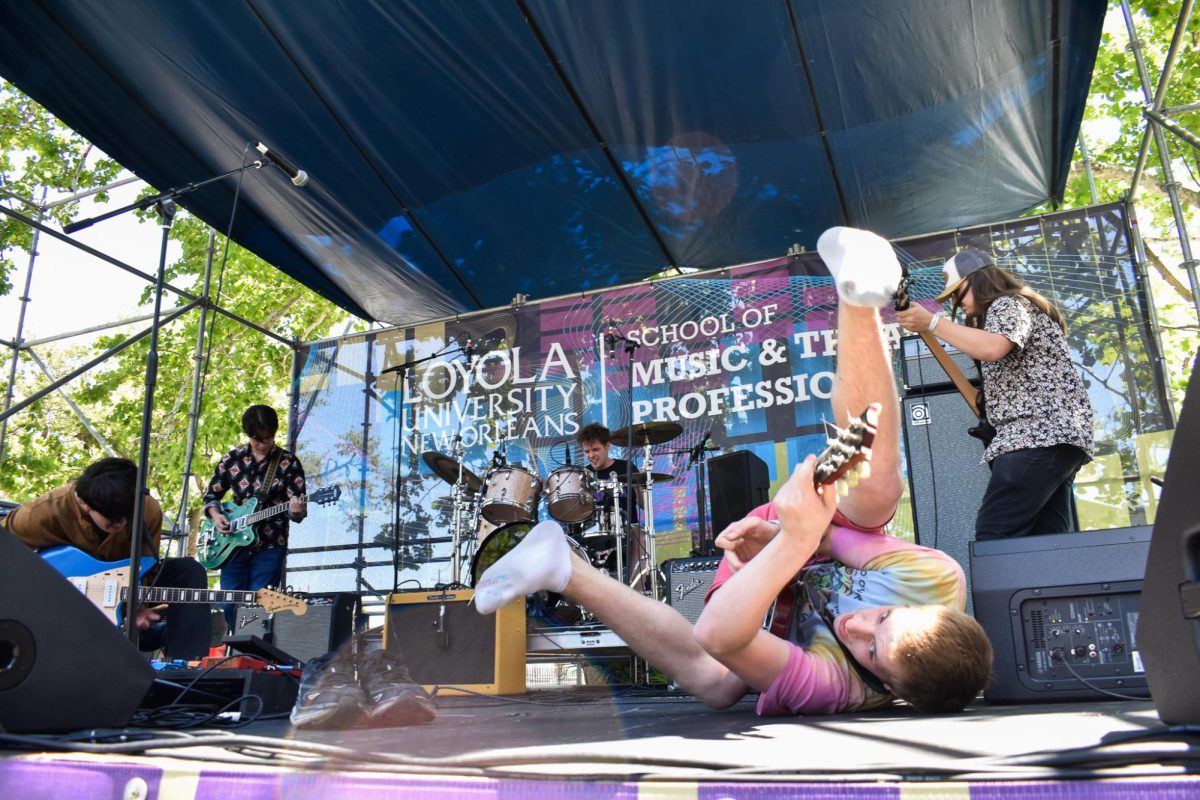Planet of the Little Green Men lead singer and guitarist Ben Heil rolls around on the Esplanade in the Shade Stage at the New Oreans Jazz Museum, sponsored by Loyola, on April 12, 2024. Sophia Maxim/ The Maroon.