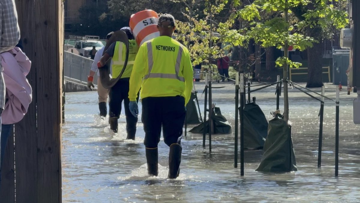 Sewage and Water Board workers walk near the scene of the broken water pipe on March 12. 