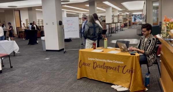 Xavi Lacayo, a Loyola career coach, sitting at a check-in desk at the Career Development Center’s Wolf Pack Power Hour event on March 24, 2026. This event was held to connect students with Loyola alumni to aid students in finding jobs and internships after college.